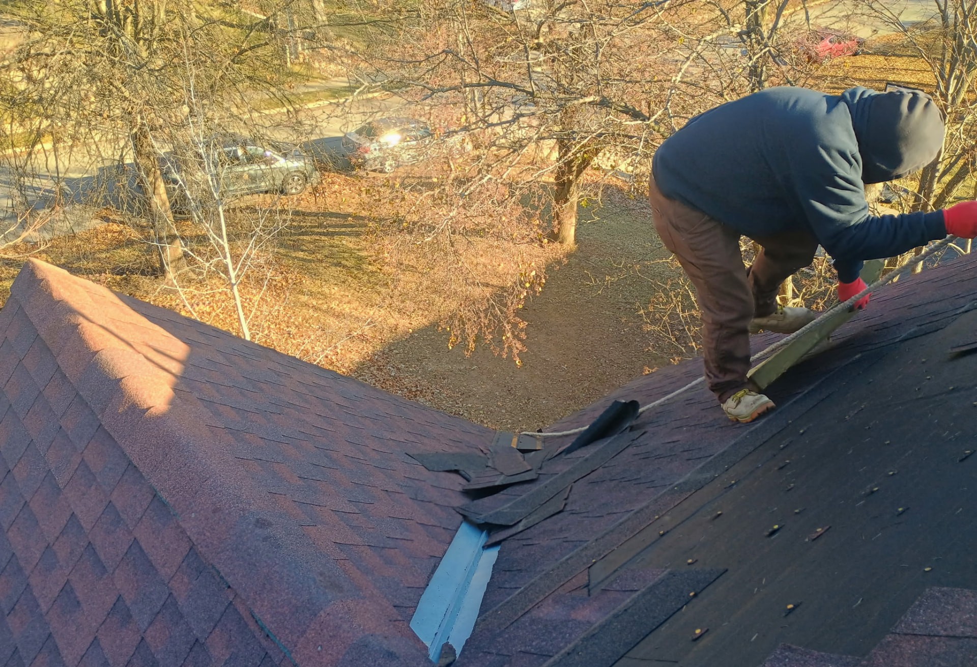 Kan Exteriors crew member repairing dark asphalt shingles on a steep residential roof